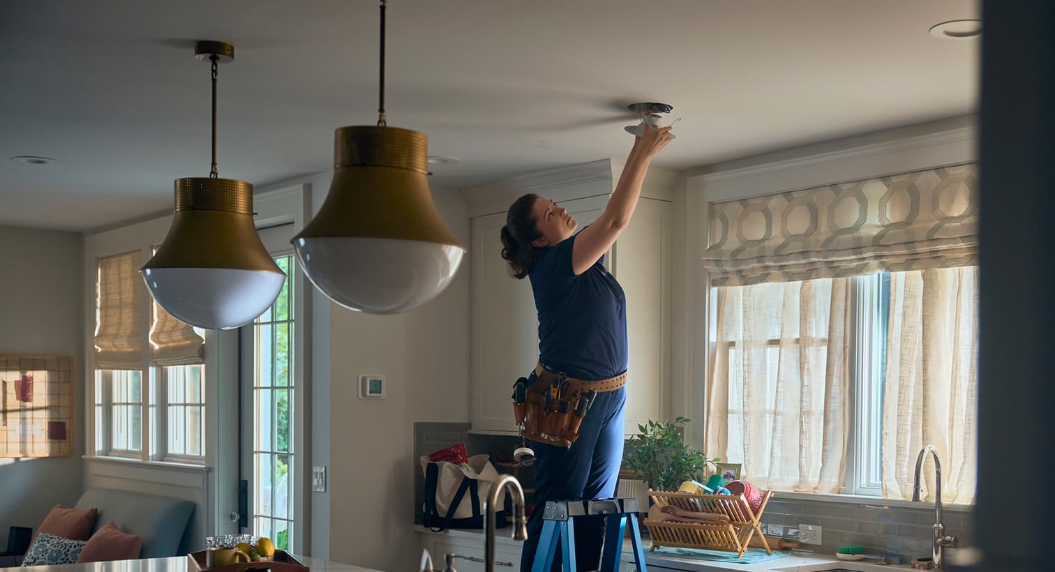 A professional Nicholson electrician standing on a ladder to install modern recessed ceiling lights during a residential electrical installation service.