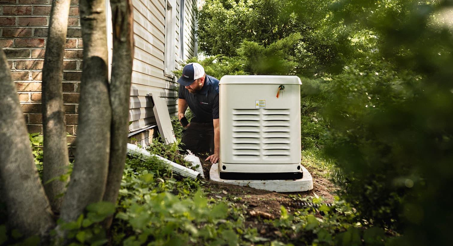 A professional Nicholson technician inspects a large, beige whole-home standby generator installed on a concrete pad outside a residential house.