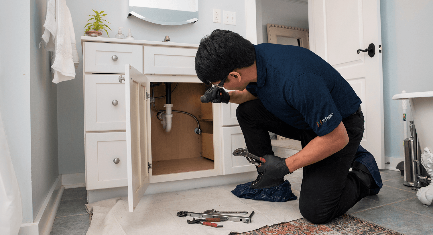 Man looking at the drain under a bathroom sink