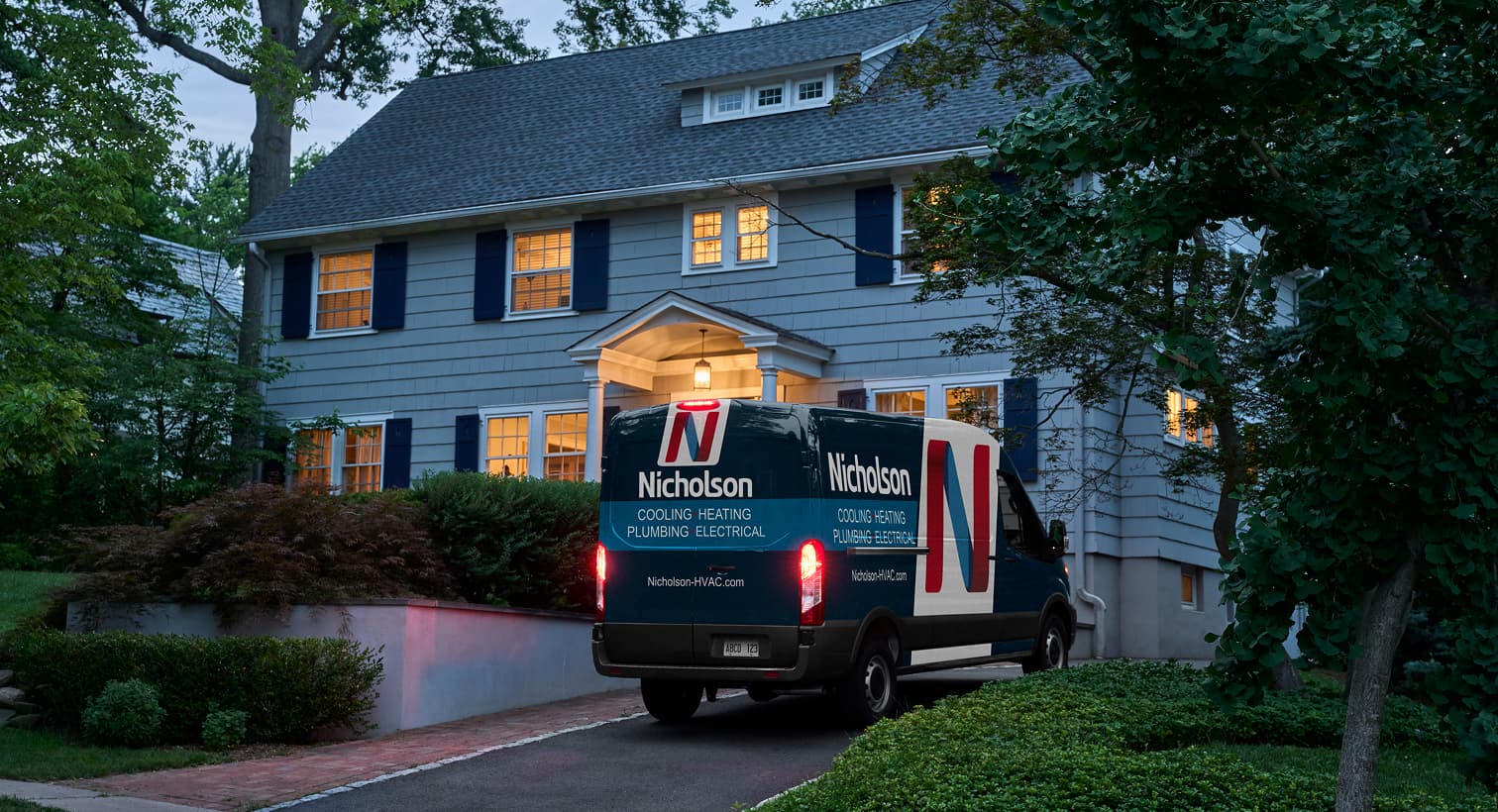 A Nicholson service van parked in a residential driveway at night, arriving to provide 24/7 emergency heating repair services.